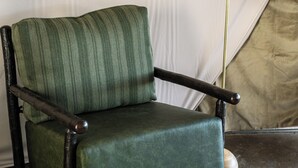 A green upholstered chair with wooden armrests and legs, positioned on a carpeted floor. - Two Capes Lookout (Cloverdale)
