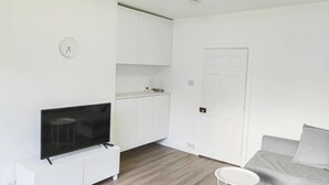 A modern living room with a flat-screen TV, a white sofa, and a small white side table. - Lovely flat near University of Aberdeen (Aberdeen)