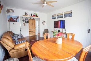 Uma sala de jantar com mesa de madeira, cadeiras e um vaso com flores.