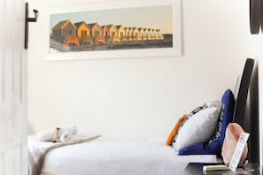 A hotel room with a bed, a framed picture on the wall, a remote control, and a salt lamp.