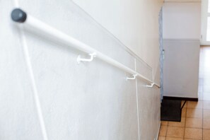 A corridor with a white wall, a door, and a tiled floor.