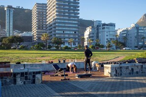 Um parque com equipamentos de ginástica, área gramada e edifícios ao fundo.