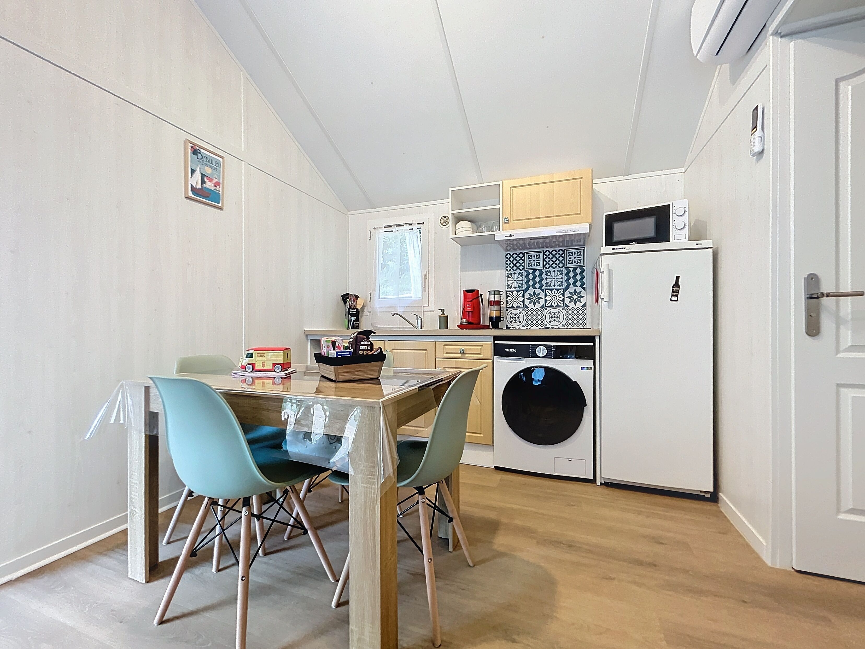 A compact kitchen with a washing machine, microwave, and a small dining area with two chairs.