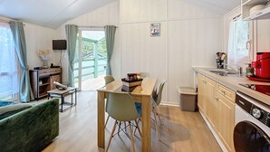Una cucina compatta con mobili in legno, un lavandino, una macchina del caffè rossa e una lavatrice.