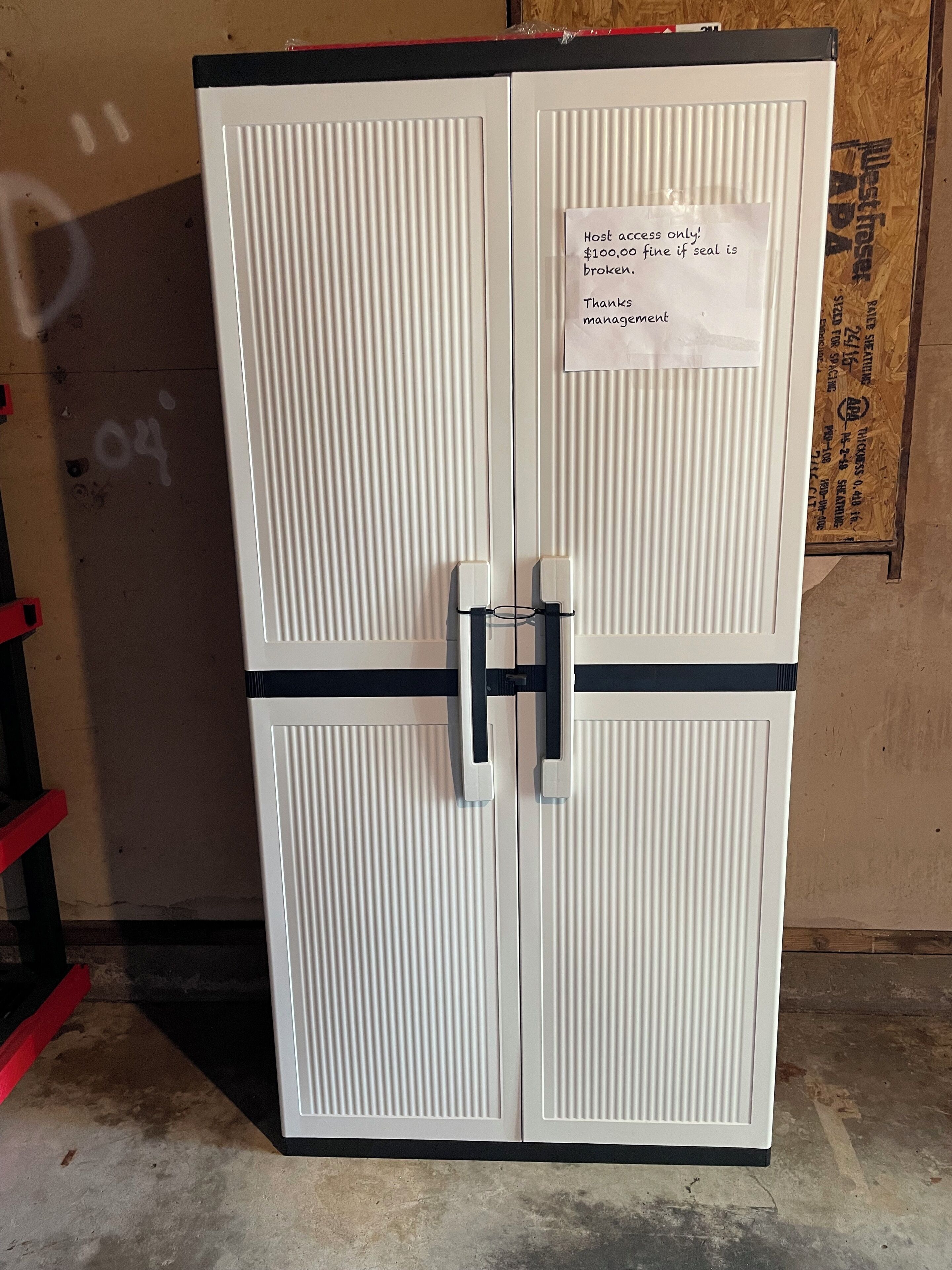 A white double-door cabinet with a note attached.