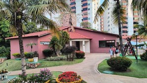 A pink building with a red roof, surrounded by palm trees and flower beds. - Hot Springs Hotel Caldas Novas-GO (Caldas Caldas Novas)