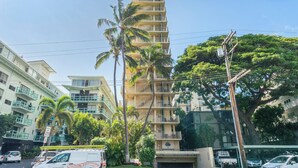 A multi-story hotel with balconies, palm trees, and a clear blue sky. - Charming Studio Apartment with WiFi, AC in beautiful Diamond Head Beach Park! (Honolulu)