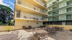 A multi-story building with outdoor seating areas, including tables and chairs, and balconies. - Charming Studio Apartment with WiFi, AC in beautiful Diamond Head Beach Park! (Honolulu)