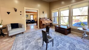 A spacious living room with a piano, a sofa, and a clear glass table.