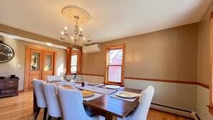A dining room with a wooden table set for six, surrounded by six chairs.