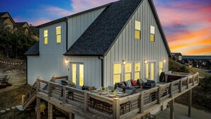 Une maison à deux étages dotée d’une terrasse, comprenant un espace repas avec mobilier d’extérieur et un jacuzzi.