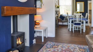 A living room with a fireplace, a dining area with a table and chairs, and a kitchen visible through an open doorway.