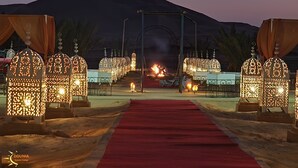 A luxury camp with a red carpet walkway, ornate lanterns, and a mountainous backdrop. - Adrar Luxury Camp (Rissani)