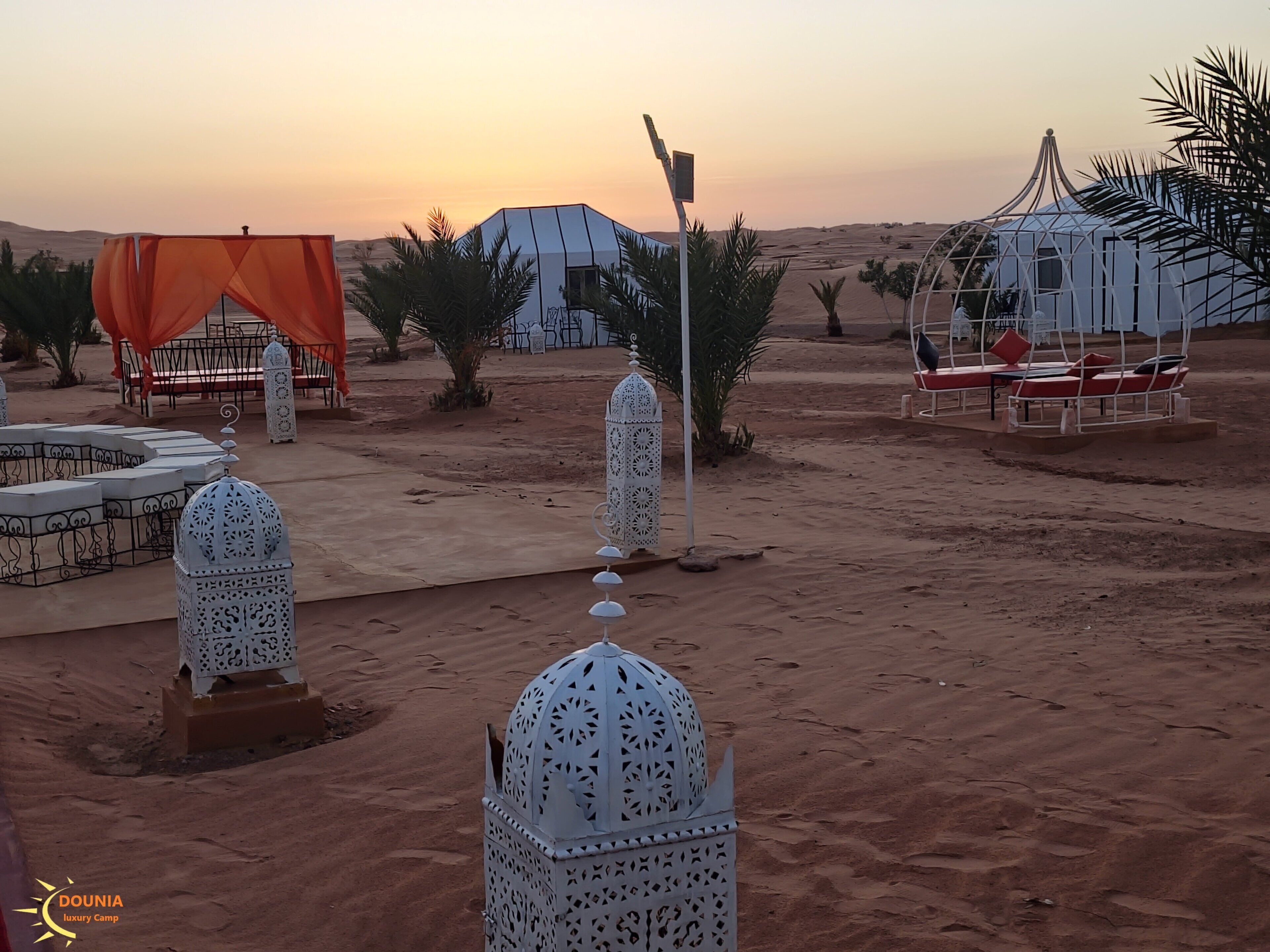 A desert camp with tents, lounge chairs, and decorative lanterns.