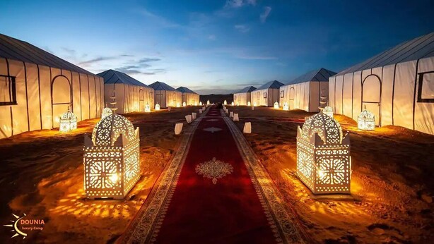 A row of tents with a red carpet and ornate lanterns in the center. - Adrar Luxury Camp (Rissani)