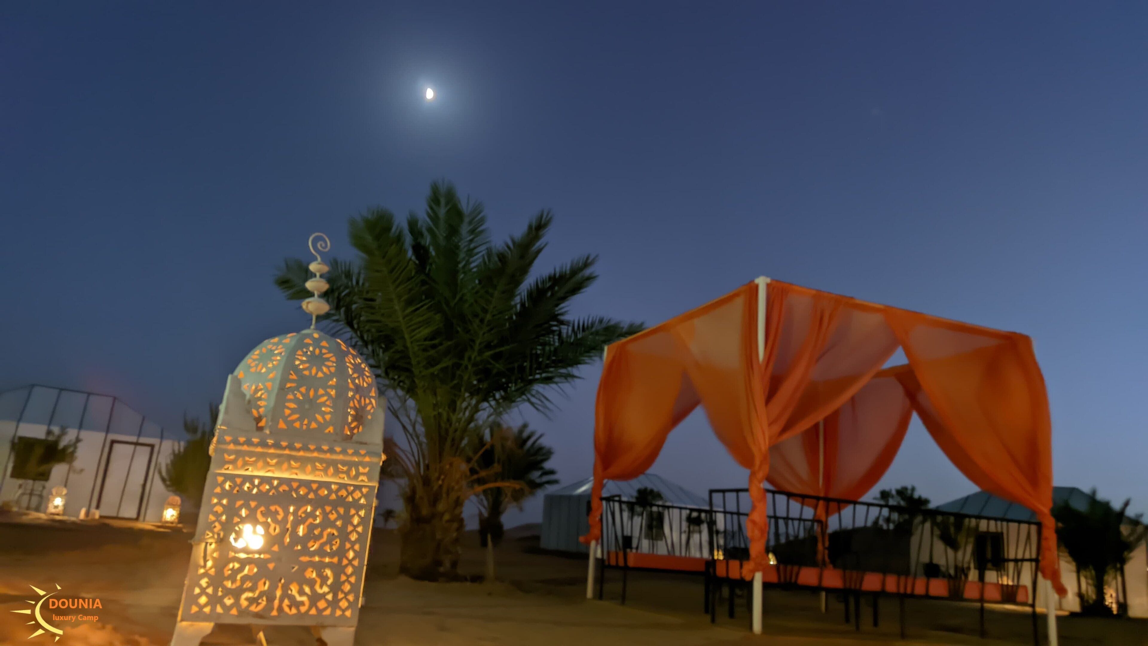 A night scene with a moonlit sky, a decorative lantern, and a tent-like structure.