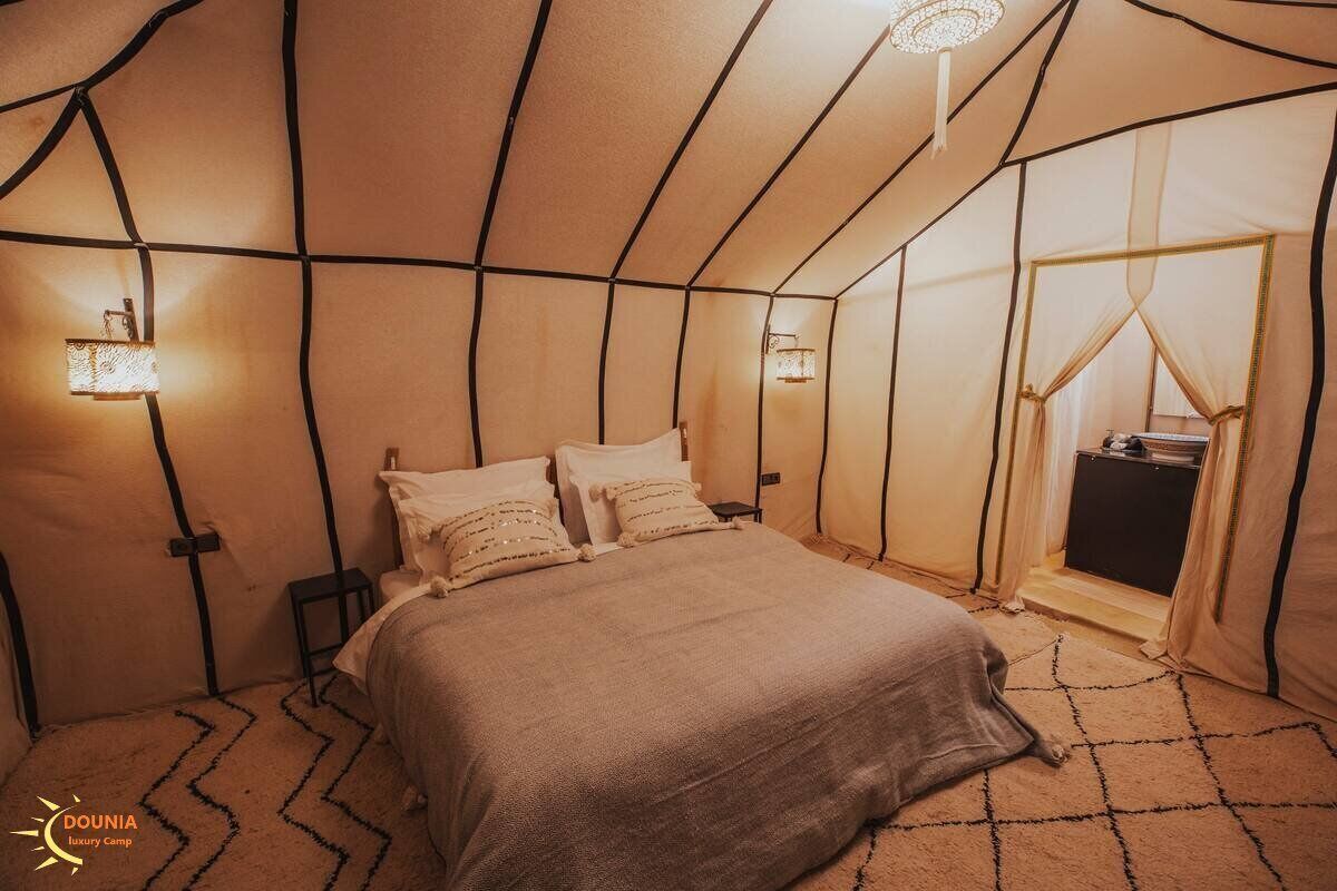 A cozy, tent-like bedroom with a bed, pillows, and two wall-mounted lamps.