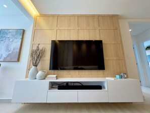 Relax in this stylish living room with a large flat-screen TV, entertainment unit, and comfortable seating area.