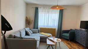 A cozy living room with a sofa, a small table, a cabinet, and a radiator. - Cosy house Sables d'Olonne, 4 pers, town center (LES SABLES D'OLONNE)