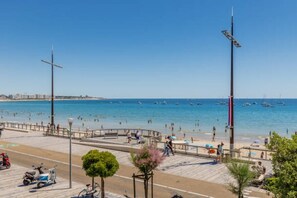 Une promenade en bord de mer offrant une vue dégagée sur la mer, un chemin piétonnier pavé et quelques scooters garés.