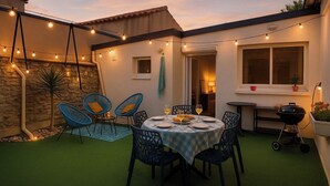 An outdoor patio with a round table set for dining, surrounded by blue chairs, and string lights overhead. - Cosy house Sables d'Olonne, 4 pers, town center (LES SABLES D'OLONNE)