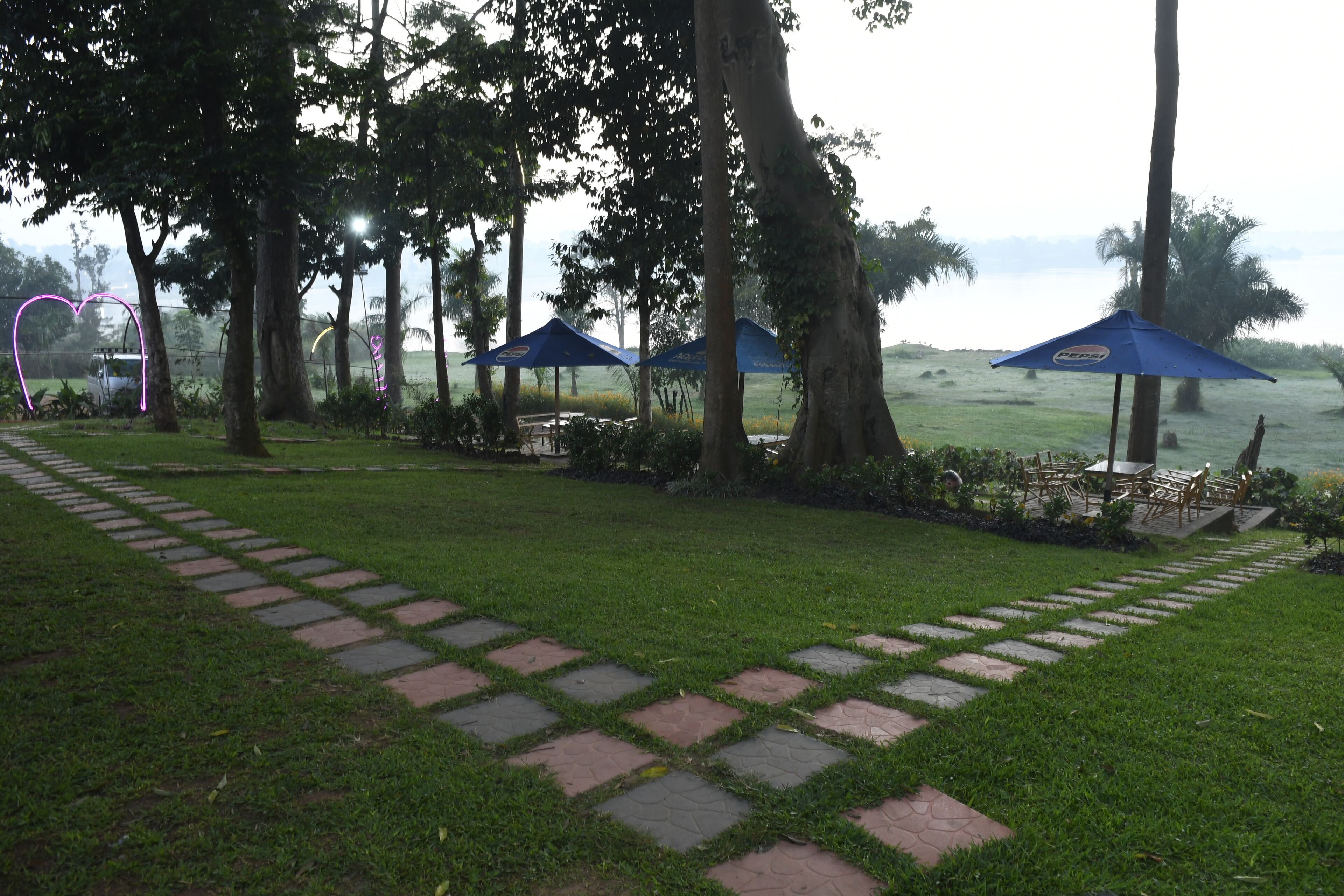 A garden area with a paved walkway, blue umbrellas, and outdoor seating.