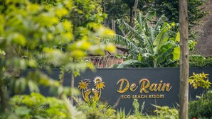 A sign for De Rain Eco Beach Resort surrounded by lush greenery. - De Rain Eco Beach Resort (Entebbe)