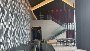 A modern interior with a staircase, seating areas, and a patterned wall.