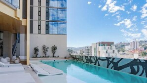 A modern building with a rooftop pool, outdoor seating, and a view of the cityscape.