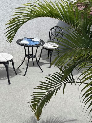 A round outdoor table with two chairs, each with a cushion.