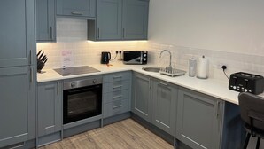 A modern kitchen with grey cabinets, a built-in oven, a microwave, a sink, and a toaster. - Charming 2-bedroom apartment in Cardiff city center,  super fast WiFi Netflix (Cardiff)