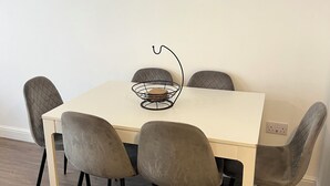 A dining table with six chairs, a small decorative item on the table, and three leaf-patterned wall art pieces. - Charming 2-bedroom apartment in Cardiff city center,  super fast WiFi Netflix (Cardiff)