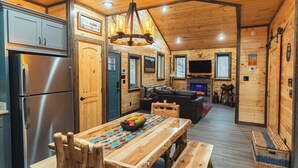 A wooden cabin interior with a kitchen, dining area, and living room. - New Build! Charming Wears Valley Cabin! Close to National Park and Attractions! (Sevierville)