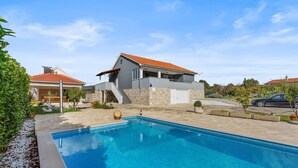 A modern house with a swimming pool, a covered patio, and a stone wall. - Lovely home in Cvrljevo with private swimming pool, can be inside or outside (Cvrljevo)