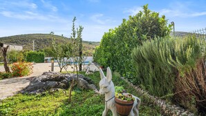 A garden with a white donkey statue holding a planter, surrounded by various plants and a pool in the background. - Lovely home in Cvrljevo with private swimming pool, can be inside or outside (Cvrljevo)