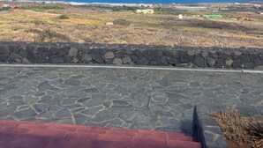Una terraza empedrada con vista al océano y edificios distantes.