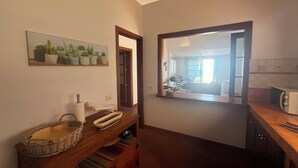 Una cocina con encimera de madera, un lavabo y un espejo que refleja un comedor.
