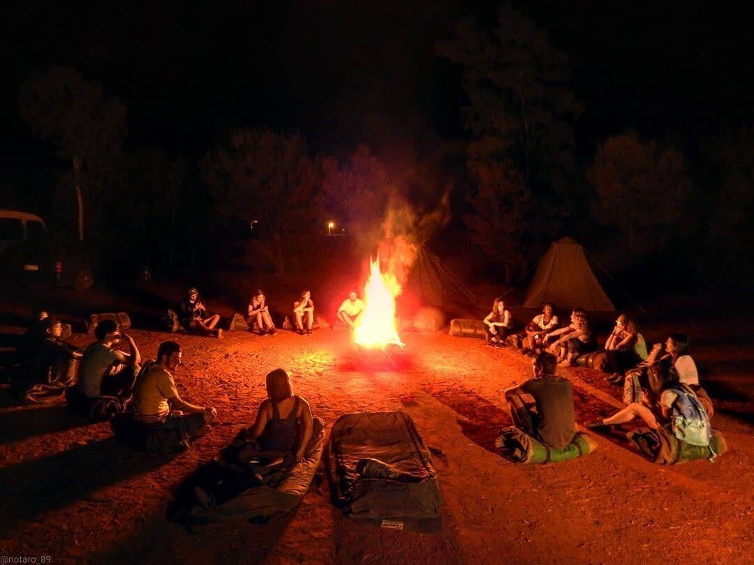 Un grupo de personas sentadas alrededor de una fogata por la noche.