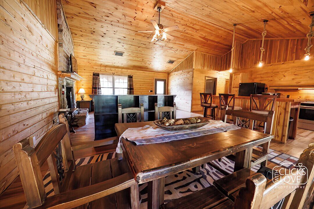 A wooden cabin interior with a dining area, kitchen, and bar.