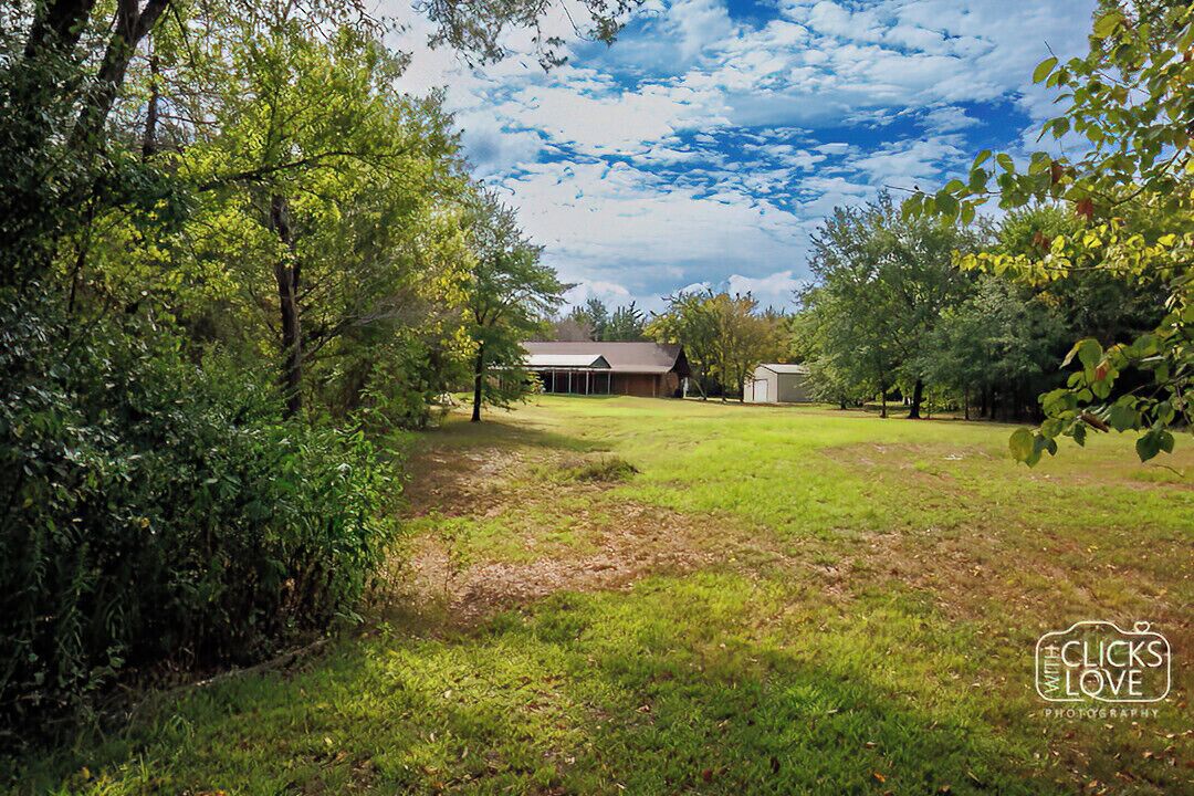 A rural property with a house, a fenced yard, and surrounding trees.