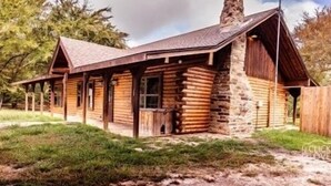 Una cabana de fusta amb fonaments de pedra, un porxo de fusta i una xemeneia.