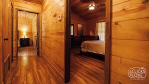 Interior d'una cabana de fusta amb un passadís que condueix a un dormitori.
