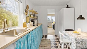 Une cuisine moderne dotée d’une grande fenêtre, d’un évier et d’un coin repas avec une table et des chaises.