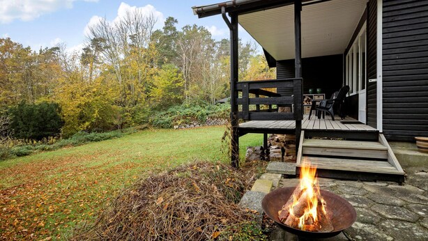 Une terrasse en bois avec un foyer, une véranda et un mur en pierre.