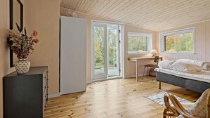 Une chambre avec un lit, un bureau et une chaise. Il y a une fenêtre et une porte.