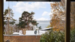 Une vue d’une cabane, avec un lac et des arbres en arrière-plan.