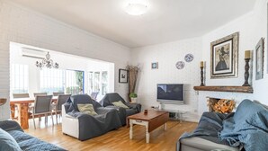 Un salon spacieux doté d’une cheminée, d’un téléviseur et d’un coin repas avec une table et des chaises en bois.