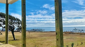 Eine Holzterrasse mit Blick auf den Ozean und einem Pier im Hintergrund.