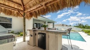 Zona de cocina al aire libre con parrilla, barra y asientos.