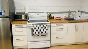 A kitchen with a stove, microwave, and refrigerator. There are cabinets and a sink. - Cozy basement place  (Kentville)